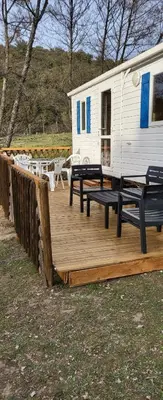 a wooden deck with picnic tables and a trailer at Le coin tranquille in Morosaglia