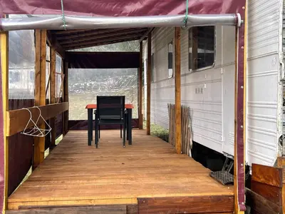 a porch with a table and a chair on it at La Caravane LE NID DOUILLET in Ponte-Leccia