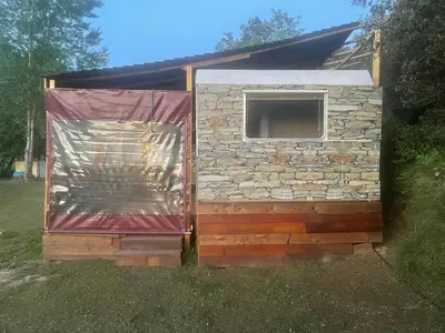 a cabin with a stone wall and a window at La Caravane LE NID DOUILLET in Ponte-Leccia