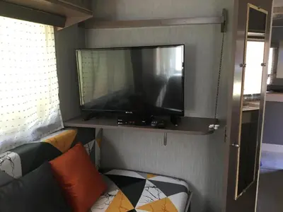 a flat screen tv on a shelf in a living room at La Caravane LE NID DOUILLET in Ponte-Leccia