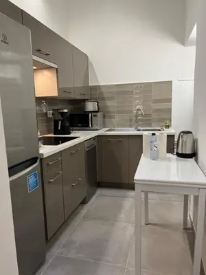a kitchen with stainless steel appliances and a white table at Appartement T2 vieille ville d’Ajaccio in Ajaccio