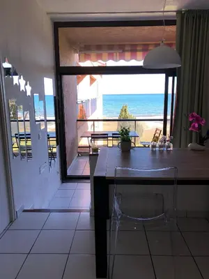 a dining room with a table and a view of the ocean at Joli T2 les pieds dans l’eau , piscine tennis.... in San-Nicolao