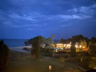 a view of a resort at night with the ocean at Joli T2 les pieds dans l’eau , piscine tennis.... in San-Nicolao
