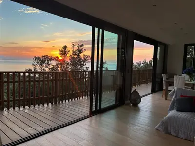 a living room with a balcony with a view of the ocean at Villa l'Alpana en bois vue mer a 180 degres in Sari Solenzara