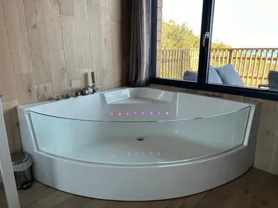 a large white bath tub in a room with a window at Villa l'Alpana en bois vue mer a 180 degres in Sari Solenzara
