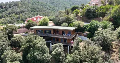 a house on a hill in the middle of trees at Villa l'Alpana en bois vue mer a 180 degres in Sari Solenzara