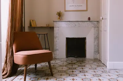 a living room with a chair and a fireplace at L'Orangeraie d'Afa in Afa
