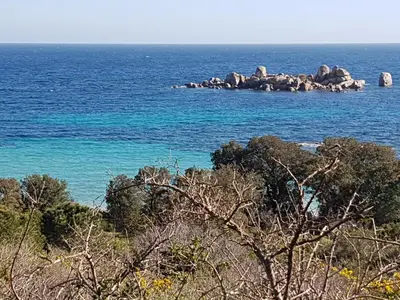 a beach with the ocean and mountains in the background at Maison avec piscine chauffée in Porto-Vecchio