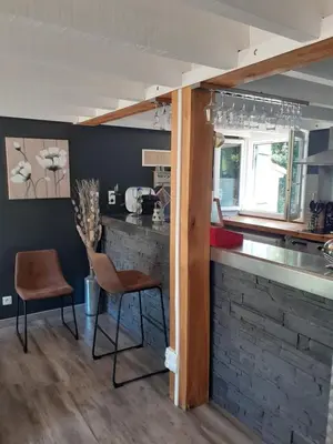 a kitchen with a brick counter and two chairs at Maison avec piscine chauffée in Porto-Vecchio