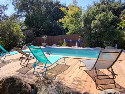a swimming pool with two chairs and a table at Maison avec piscine chauffée in Porto-Vecchio