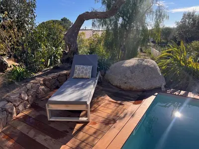 a chair sitting on a deck next to a swimming pool at Un petit paradis in Pinarellu