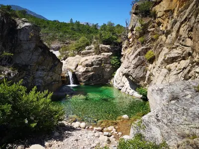 a pool of water in a canyon with a waterfall at Un petit paradis in Pinarellu