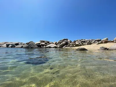 a beach with rocks and the clear water at Un petit paradis in Pinarellu