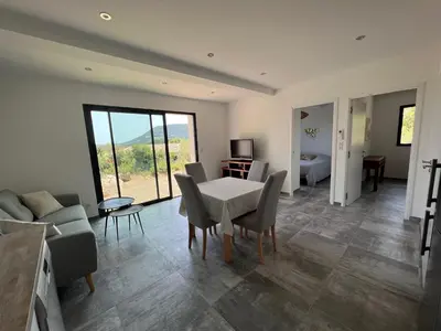 a living room with a table and chairs and a couch at Un petit paradis in Pinarellu