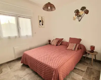 a bedroom with a bed with a red comforter and two windows at Petite maison en pierre in Afa