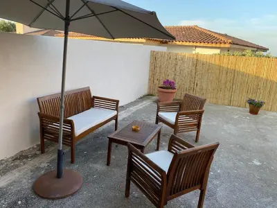 three chairs and a table with an umbrella on a patio at Petite maison en pierre in Afa