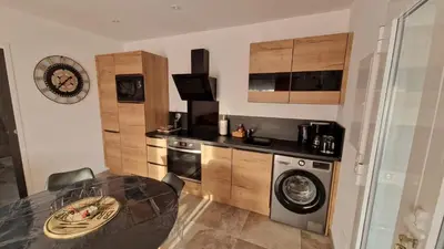 a kitchen with a table and a washing machine at Petite maison en pierre in Afa