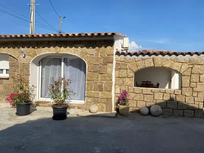 a stone house with three potted plants in front of it at Petite maison en pierre in Afa