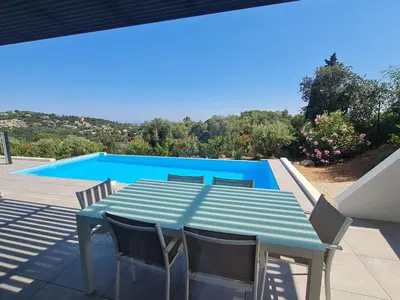 a blue table and chairs on a patio with a pool at Villa Marcaléone Corse du Sud in Cirendinu