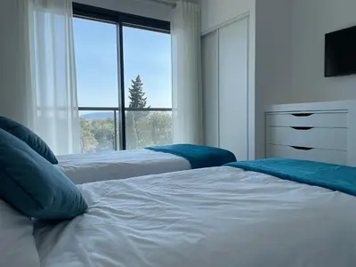 two beds in a bedroom with a large window at Villa Marcaléone Corse du Sud in Cirendinu