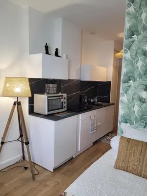 a kitchen with white cabinets and a microwave on a counter at Studio bord de mer - Plage - Piscine - Wifi in Santa-Lucia-di-Moriani