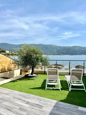 two white chairs sitting on the grass near the water at PIEDS DANS L'EAU, TIUCCIA, appartement 2-4 pers in Casaglione