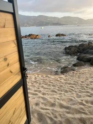 a door to a beach with the ocean and rocks at PIEDS DANS L'EAU, TIUCCIA, appartement 2-4 pers in Casaglione