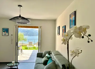 a living room with a couch and a vase with flowers at PIEDS DANS L'EAU, TIUCCIA, appartement 2-4 pers in Casaglione