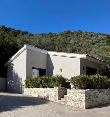 a white building with a hill in the background at Mogador in Bonifacio