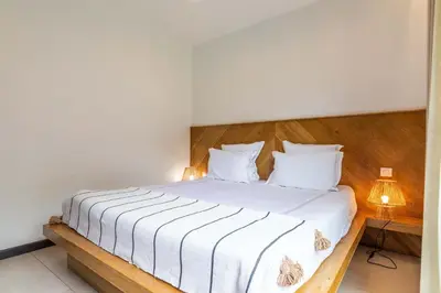 a bedroom with a white bed with a wooden headboard at Mogador in Bonifacio