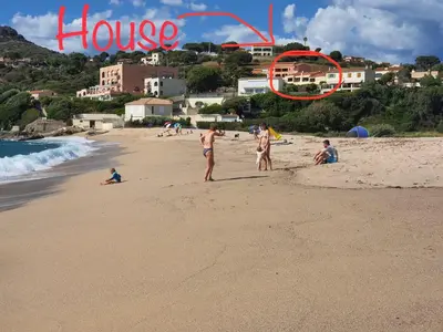 a group of people standing on a beach with a house sign at Apartment Liscia sea view, restaurant and supermarket 50m in Calcatoggio