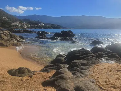 a beach with rocks in the sand and water at Apartment Liscia sea view, restaurant and supermarket 50m in Calcatoggio