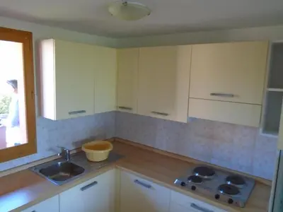 a kitchen with white cabinets and a sink and a window at VARDIOLA/PORTO VECCHIO in Pinarellu