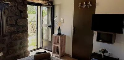 a living room with a television and a window at Chez Robert et Sylvie in Pianottoli-Caldarello