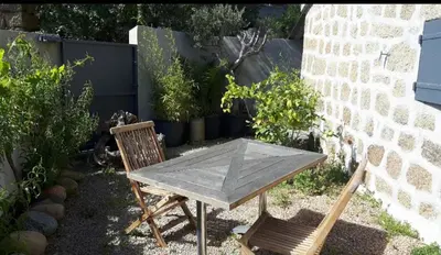 a wooden table and two chairs sitting next to a wall at Chez Robert et Sylvie in Pianottoli-Caldarello