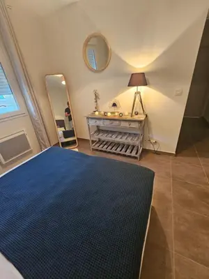 a bedroom with a blue bed and a mirror at Maison pinarello à 200 mètres de la plage in Zonza