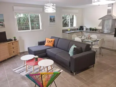 a living room with a couch and tables and a kitchen at Maison pinarello à 200 mètres de la plage in Zonza