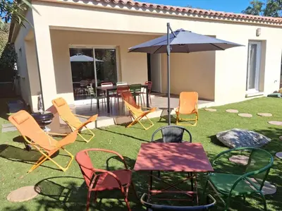 a group of chairs and an umbrella on a lawn at Maison pinarello à 200 mètres de la plage in Zonza