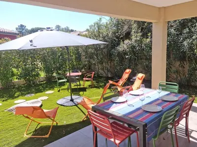 a patio with a table and chairs and an umbrella at Maison pinarello à 200 mètres de la plage in Zonza
