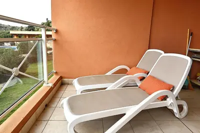 two chairs on a balcony with an open window at Les Sanguinaires N'16 - T2 Vue Mer, Piscine, Plage in Ajaccio