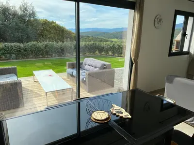 a living room with a glass table and a large window at Brindingaccia in Propriano