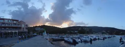 a group of boats docked in a harbor with a fire in the background at U Caseddu Di Minnana in Petreto-Bicchisano