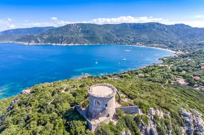 an old tower on a hill next to a body of water at U Caseddu Di Minnana in Petreto-Bicchisano