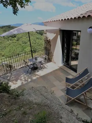 a patio with a table and an umbrella at U Caseddu Di Minnana in Petreto-Bicchisano