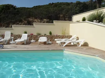 a pool with chaise lounge chairs and a patio at Gîtes Sassone, piscine, jacuzzi et vue mer panoramique sur Ajaccio in Alata