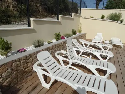 a row of white lounge chairs on a deck at Gîtes Sassone, piscine, jacuzzi et vue mer panoramique sur Ajaccio in Alata
