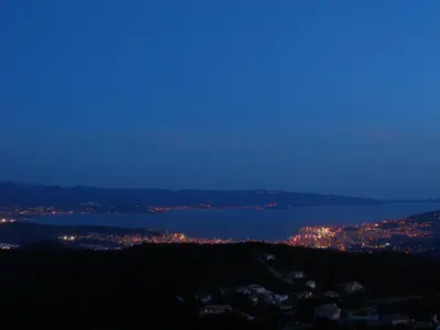 a view of a city and the water at night at Gîtes Sassone, piscine, jacuzzi et vue mer panoramique sur Ajaccio in Alata
