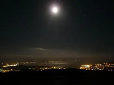 a full moon rising over a city at night at Gîtes Sassone, piscine, jacuzzi et vue mer panoramique sur Ajaccio in Alata