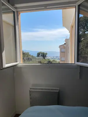 a bedroom with a window with a view of the ocean at Charmant T2 proche de la plage et au calme in Ajaccio