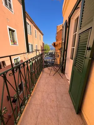 a balcony with a green door and a table at Appartement T2 Vieux Port d'Ajaccio in Ajaccio